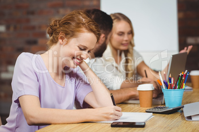 Smiling businesswoman writing on paper