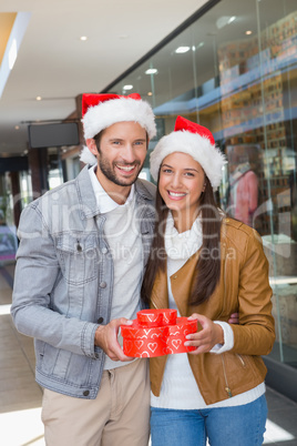 Young happy couple holding heart shaped boxes with christmas hat