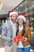 Young happy couple holding heart shaped boxes with christmas hat