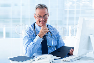 Portrait of male doctor sitting at desk in hospital