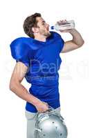 American football player holding helmet while drinking water