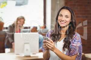 Smiling businesswoman using smartphone in office