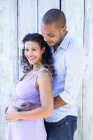 Portrait of smiling pregnant wife with husband touching belly