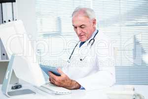 Doctor using digital tablet by computer