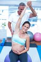 Portrait of pregnant woman stretching hand in gym