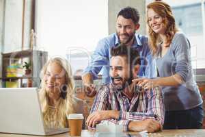 Business colleagues smiling while looking at laptop