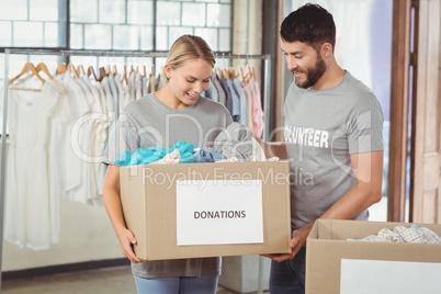 Man and woman volunteers with box standing in office