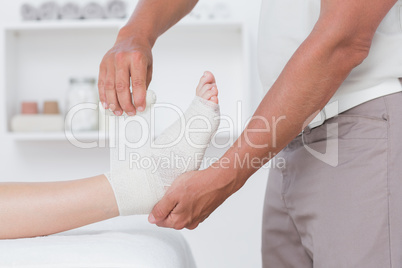 Doctor bandaging his patient ankle