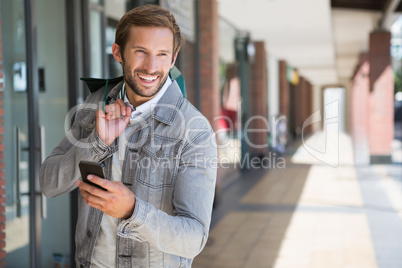 Young happy smiling man holding shopping bags and his mobile