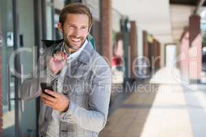 Young happy smiling man holding shopping bags and his mobile
