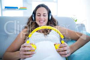 Pregnant woman listening to music on sofa