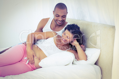 Happy pregnant wife with husband lying on bed Happy pregnant wife with husband lying on bed