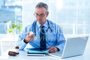 Male doctor holding pill bottle in clinic