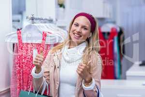 Smiling woman with shopping bags looking at camera with thumbs u