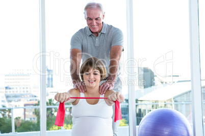 Happy pregnant woman exercising with resistance band