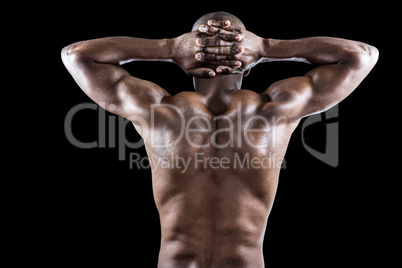 Rear view of muscular athlete stretching with hands behind head