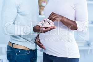 Pregnant woman giving baby shoe to husband