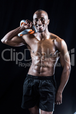 Portrait of happy muscular man holding kettlebell