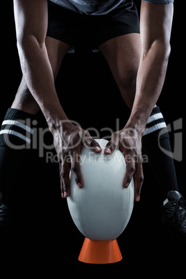 Mid section of rugby player keeping ball on kicking tee