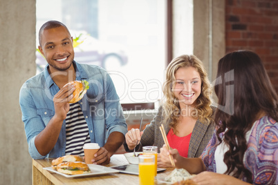 Portrait of smiling man having burger with colleagues