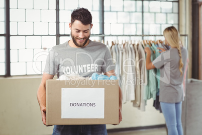 Man holding clothes donation box with woman in background