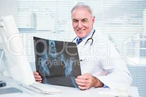 Portrait of doctor with xray sitting in front of computer