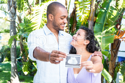Happy husband with pregnant wife holding sonogram