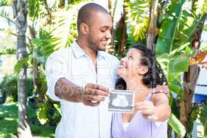 Happy husband with pregnant wife holding sonogram
