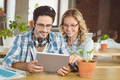 Happy business people looking at digital tablet in creative offi