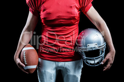 Mid section of sportsman holding American football and helmet