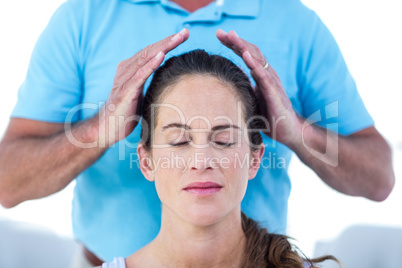 Therapist performing reiki on young woman