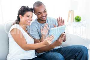 Happy couple waving at tablet
