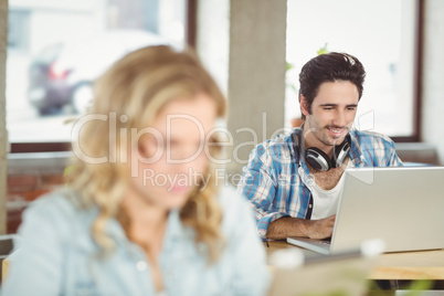 Smiling handsome business man using laptop in office