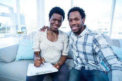 Man with pregnant wife writing on notepad