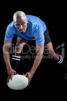 Portrait of sportsman bending and holding ball while playing rug