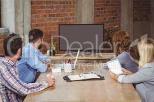 Business people looking towards screen while sitting in office