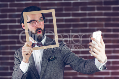 Fashionable man taking selfie while holding frame
