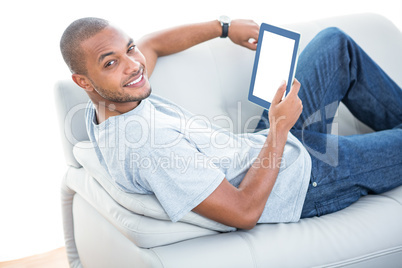 Portrait of young man with tablet on sofa