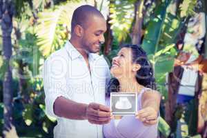 Happy man with pregnant wife holding sonogram