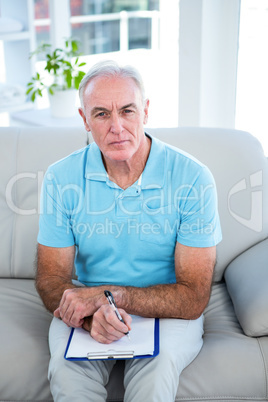 High angle view of thoughtful senior man with clipboard