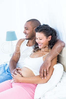 Husband sitting on bed with pregnant wife