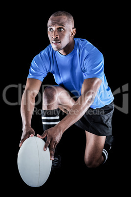 Rugby player holding ball while kneeling