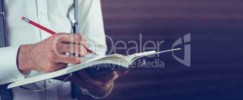 Midsection of businessman writing in his notebook