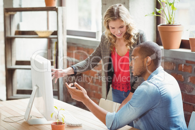 Man and woman pointing towards computer