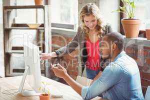Man and woman pointing towards computer