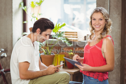 Portrait of woman with digital tablet while man using smartphone