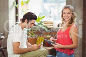 Portrait of woman with digital tablet while man using smartphone