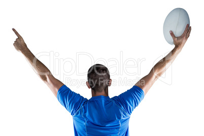 Rear view of rugby player holding ball with arms raised