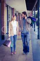 Smiling couple walking hand in hand with shopping bags