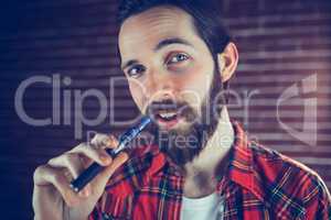 Portrait of confident man smoking electronic cigarette